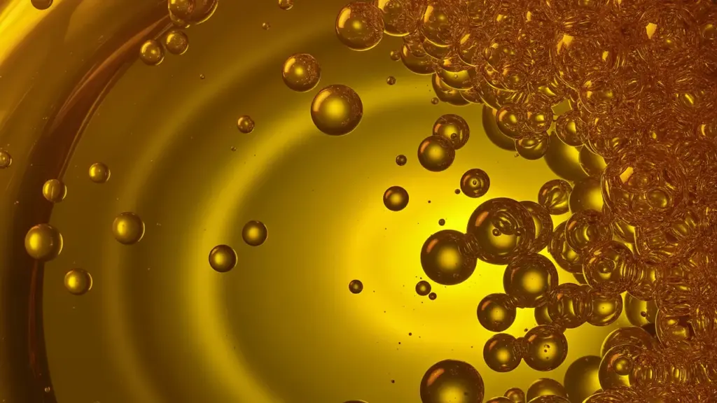 Imagen macro de aceite usado con burbujas doradas flotando sobre un fondo amarillo intenso, representando reciclaje y gestión sostenible de residuos.