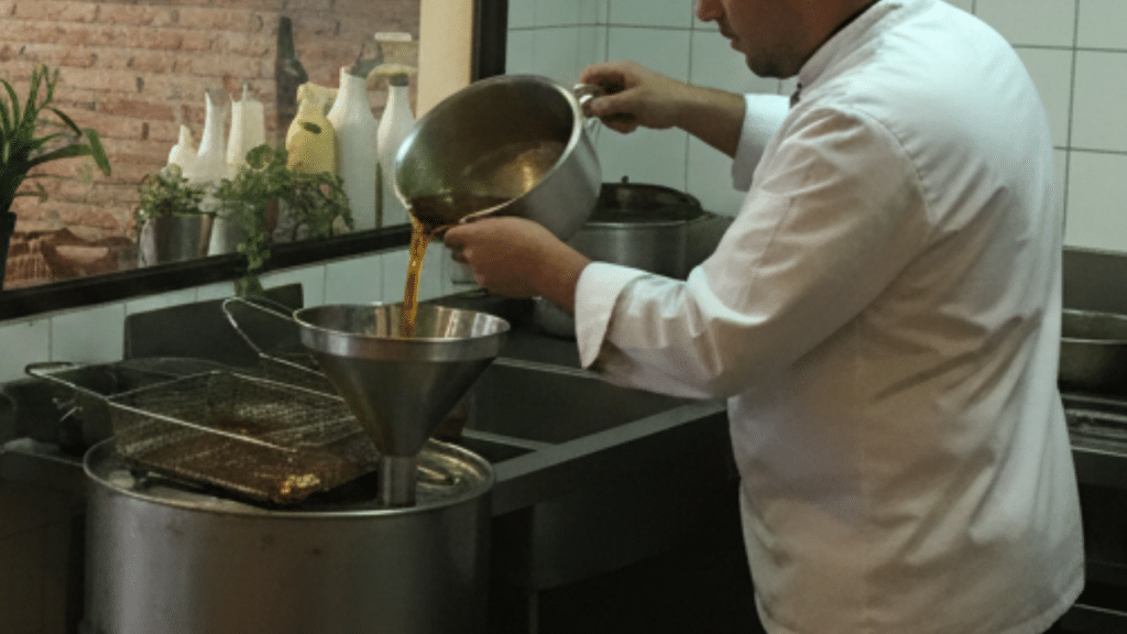 Operario gestionando aceite usado en cocina profesional de restaurante